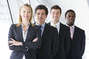 Four businesspeople standing in corridor smiling