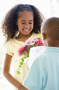 Young boy giving young girl flowers and smiling