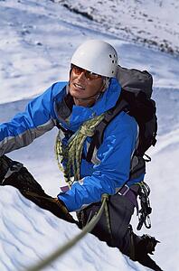 Mountain climber going up snowy mountain (selective focus)