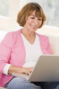 Woman in living room with laptop smiling