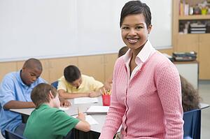 Students in class writing with teacher in foreground (selective focus)