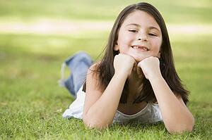 Young girl outdoors lying in grass and smiling (selective focus)