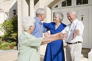 Two senior couples greeting each other with open arms
