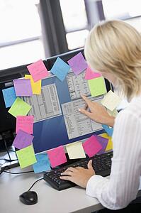Businesswoman in office pointing at monitor with notes on it