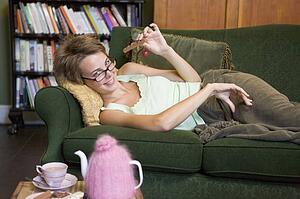 Young woman lying on sofa at home eating chocolate