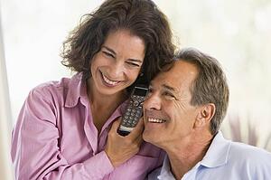 Couple indoors using telephone smiling