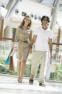 Couple walking in mall holding hands and smiling (selective focus)