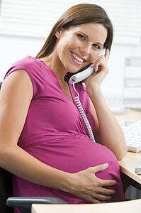 Pregnant woman at work using telephone smiling
