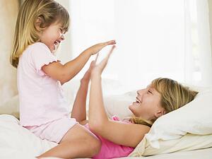 Young Girl Being Woken Up By Her Little Sister