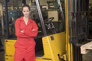 Warehouse worker standing by forklift