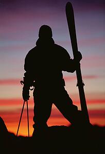 Skier standing outdoors at dusk (silhouette)