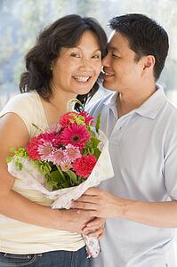 Husband and wife holding flowers smiling