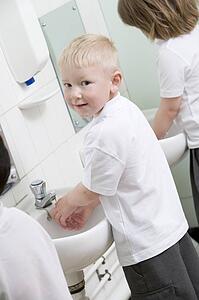 Students in bathroom at sinks washing hands