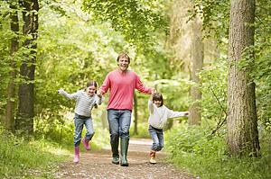 Father and daughters walking on path holding hands smiling