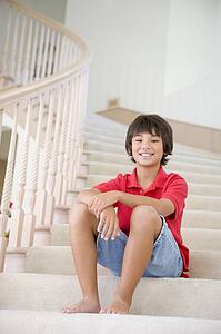 Young Boy Sitting On A Stairwell At Home
