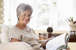 Woman in living room reading book smiling