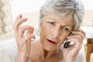 Woman indoors using cellular phone frowning