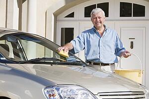 Senior man washing car outside his home