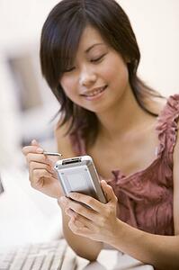 Woman in computer room using personal digital assistant smiling