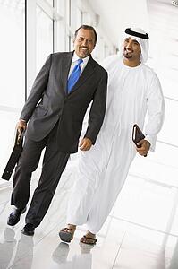 Two businessmen walking in a corridor and smiling (high key/selective focus)