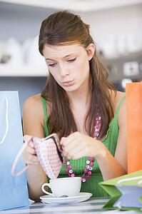 Young woman sitting at a table checking change purse