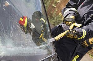 Firefighter cutting out a windshield after an accident