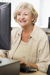 Woman sitting at a computer terminal typing (high key)