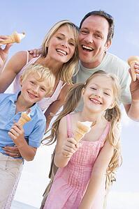 Family standing at beach with ice cream smiling