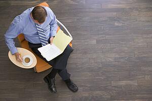 Businessman sitting indoors with coffee and folder