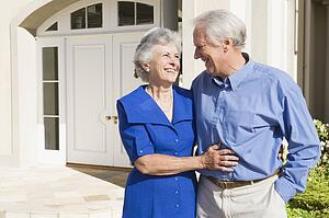 Senior couple standing outside their home