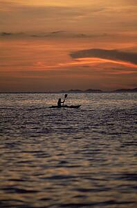 Kayaker outdoors in ocean at sunset (far away/silhouette)