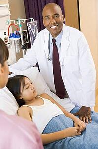 Doctor Standing In Hospital Room With Patient