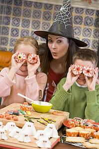Mother and two children at Halloween playing with treats and smiling