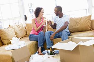 Couple toasting champagne by boxes in new home smiling