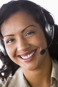 Businesswoman wearing headset in office smiling (high key/selective focus)