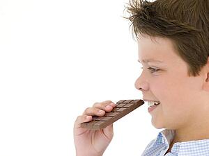 Young boy eating chocolate bar