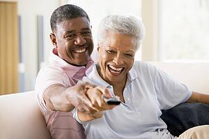 Couple in living room using remote control smiling