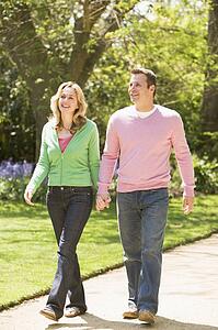 Couple walking on path holding hands smiling