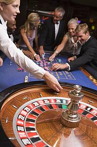 Group of people in casino playing roulette and smiling (selective focus)