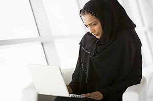 Woman sitting indoors with laptop (high key/selective focus)