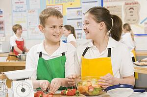 Male and female student preparing sliced fruit