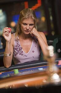 Woman in casino playing roulette and holding chip (selective focus)