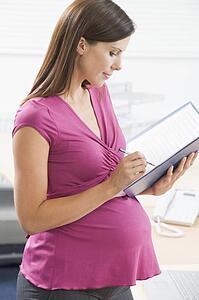 Pregnant woman at work writing in binder
