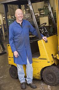 Warehouse worker standing by forklift