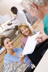 Nurses Being Handed A Clipboard At The Reception Area In A Hospital