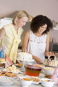 Two women at party getting sandwiches smiling