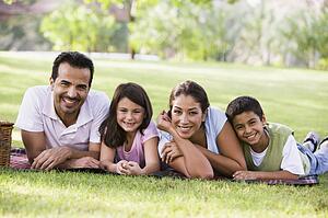 Family outdoors in park with picnic smiling (selective focus)