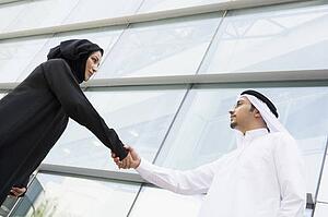 Two businesspeople outdoors by building shaking hands
