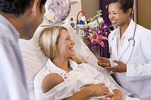 New parents with baby talking to doctor and smiling