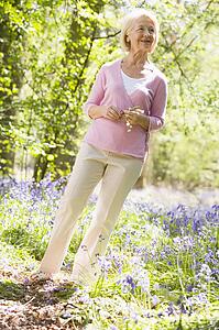 Woman standing outdoors holding flower smiling